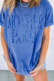 Blue oversized graphic t-shirt with "Motherhood" text, cuffed sleeves, and crew neck.