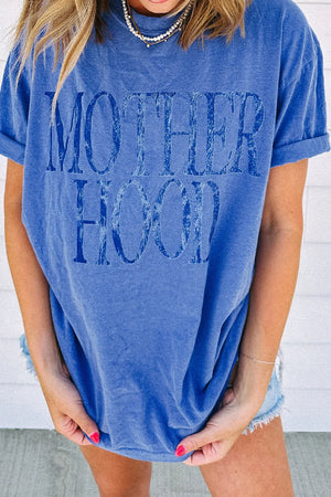Blue oversized graphic t-shirt with "Motherhood" text, cuffed sleeves, and crew neck.