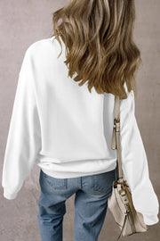 White crewneck sweatshirt with long sleeves, styled with jeans and a crossbody bag.