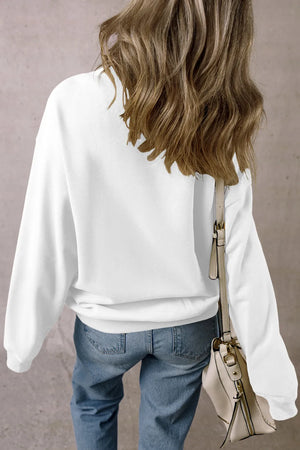 White crewneck sweatshirt with long sleeves, styled with jeans and a crossbody bag.