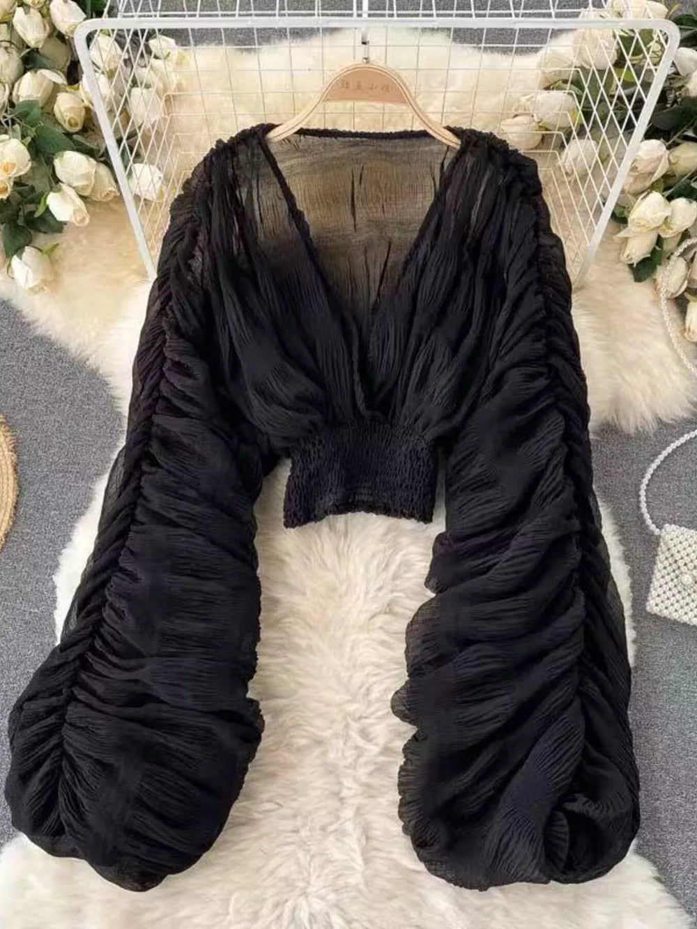 Black sheer blouse with deep V-neck and voluminous ruched sleeves.