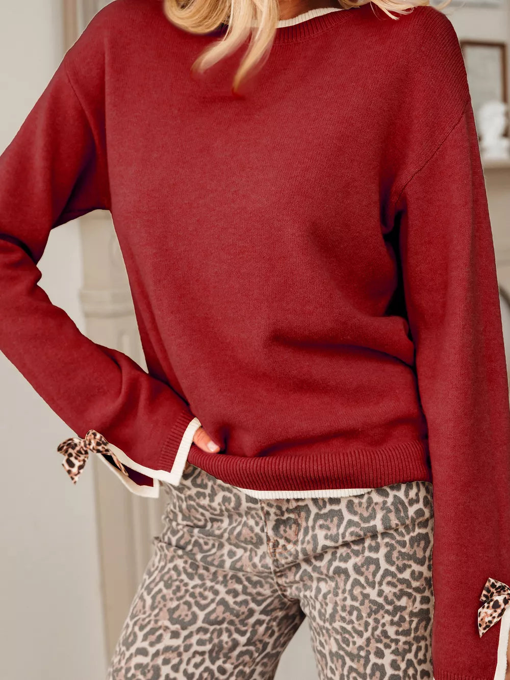 Red crew neck sweater with leopard print bow accents on sleeves and contrast trim.