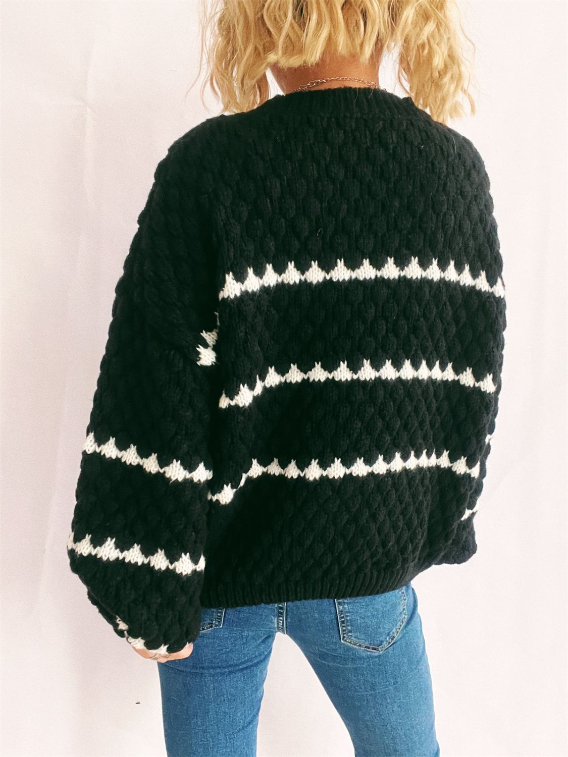 Black textured knit jumper with white chevron stripes, crew neck, long sleeves.