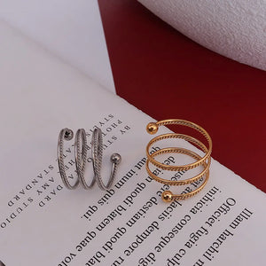 Spiral orb ring in gold and silver, featuring a twisted band and ball ends.