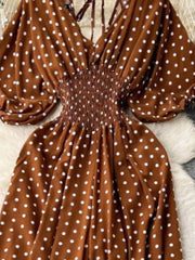 Caramel polka dot smocked romper with V-neck and balloon sleeves.