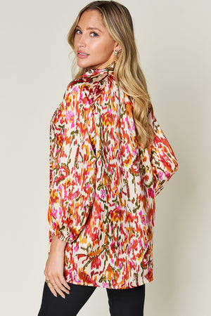 Silk tie-neck blouse with abstract ikat print in tangerine, pink, and green.