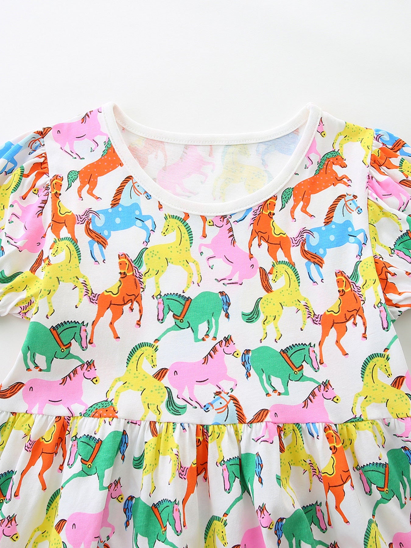 Toddler cotton dress with playful multi-color horse print and puff sleeves.