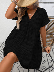 Black plaid V-neck mini dress with short sleeves and tiered skirt.