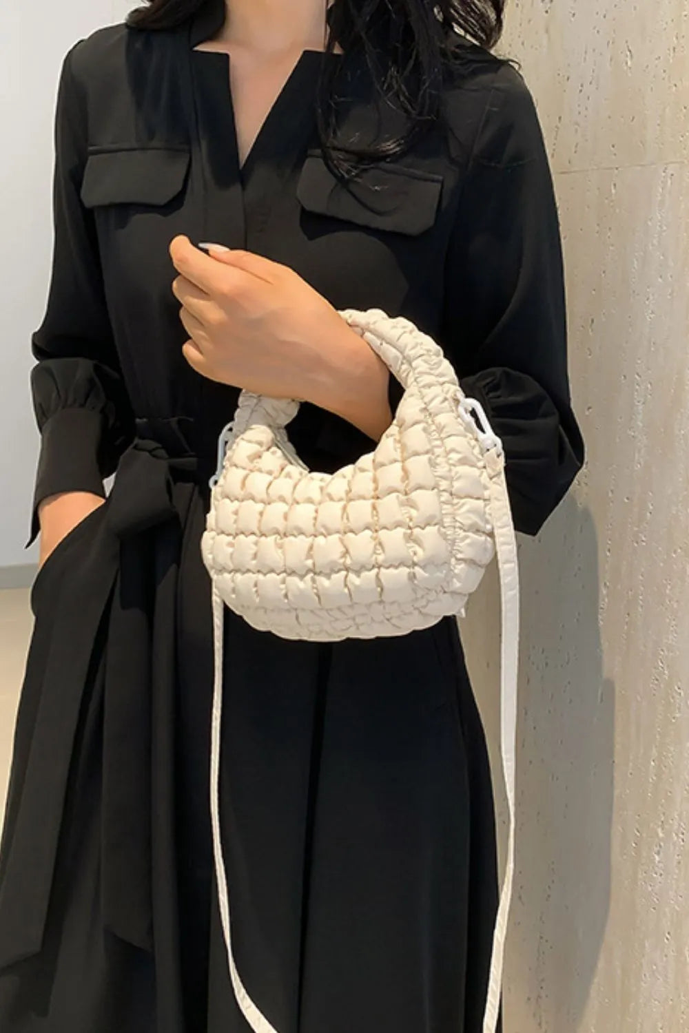 Padded crescent crossbody bag in ivory with sculptural texture and a crossbody strap.