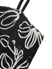 Black cami top with white floral embroidery and spaghetti straps.