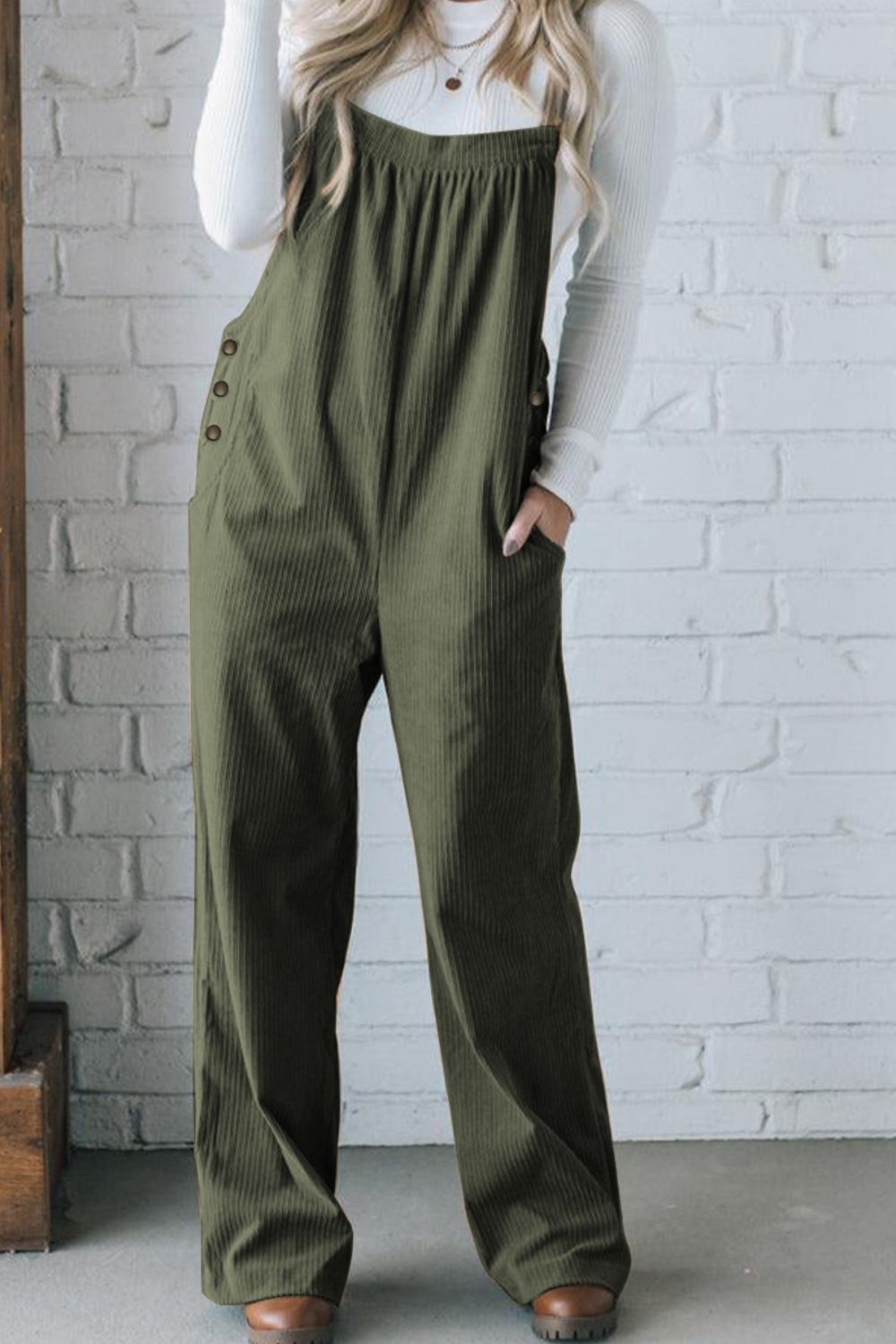 Army green corduroy wide-leg overalls with button side detail and pockets, styled with a white long-sleeve shirt.