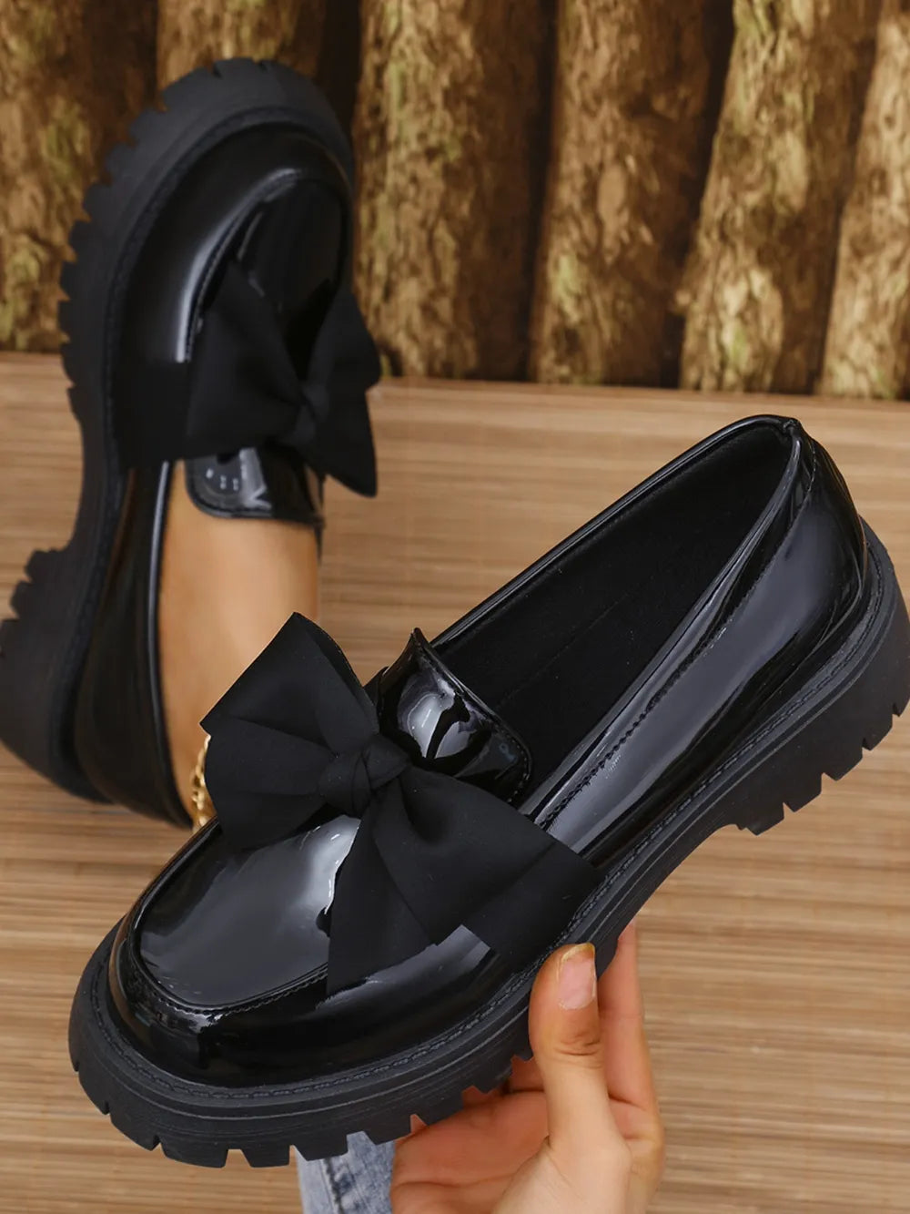 Black patent platform loafers with a large bow detail.