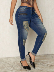 Distressed skinny jeans in medium wash denim with zip details and ripped accents.