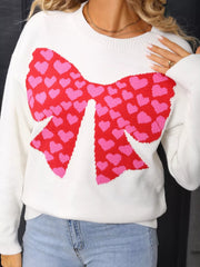 White knit sweater with red and pink heart bow graphic, round neck, long sleeves.