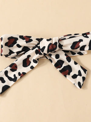 Baby bodysuit detail with leopard print and bow, 100% polyester.