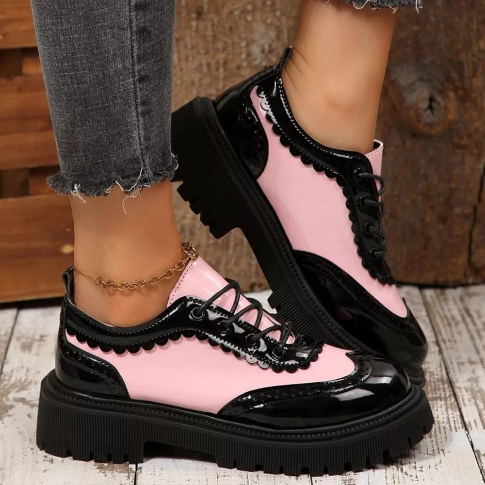 Pink and black patent leather platform loafers with brogue detailing and scalloped trim.