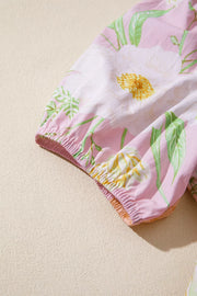 Floral tiered dress with puff sleeves in pink cotton featuring white and yellow flowers and green leaves.