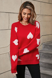 Red acrylic knit jumper with allover white heart intarsia pattern, crew neck, long sleeves.