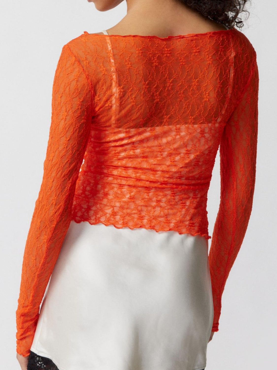 Orange lace blouse with scalloped edge and ruched detail, boat neck, long sleeves.