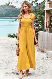 Gold smocked bodice tie-strap palazzo jumpsuit with wide legs.