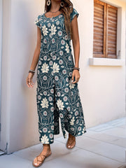 Botanical print culotte jumpsuit in dark green with short sleeves and a scoop neck.