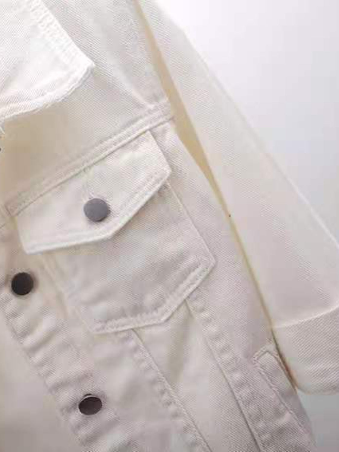 White denim trucker jacket with button-flap chest pockets and button front detail.