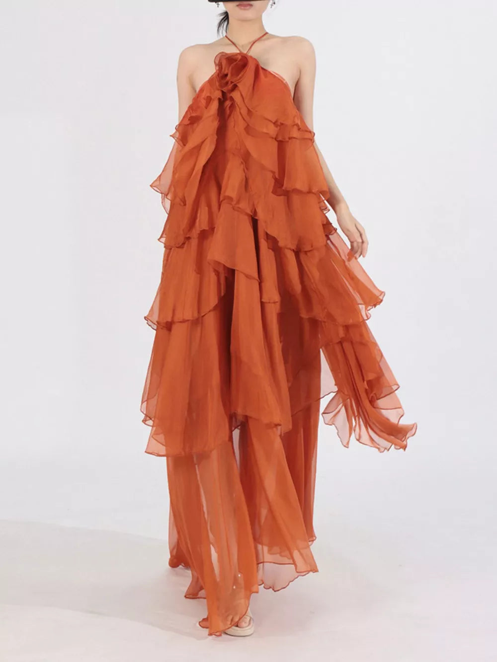 Orange cascading ruffle halter maxi dress with tiered skirt and flowy silhouette.