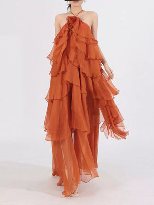 Orange cascading ruffle halter maxi dress with tiered skirt and flowy silhouette.