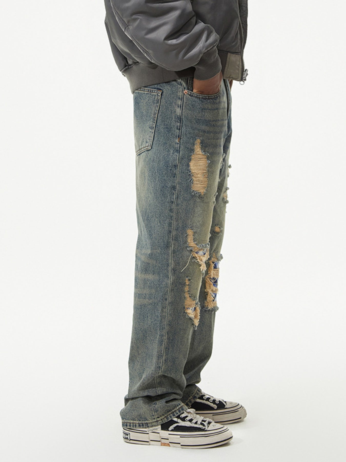 Men's distressed wide leg jeans in blue denim with rips and patches.