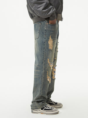 Men's distressed wide leg jeans in blue denim with rips and patches.