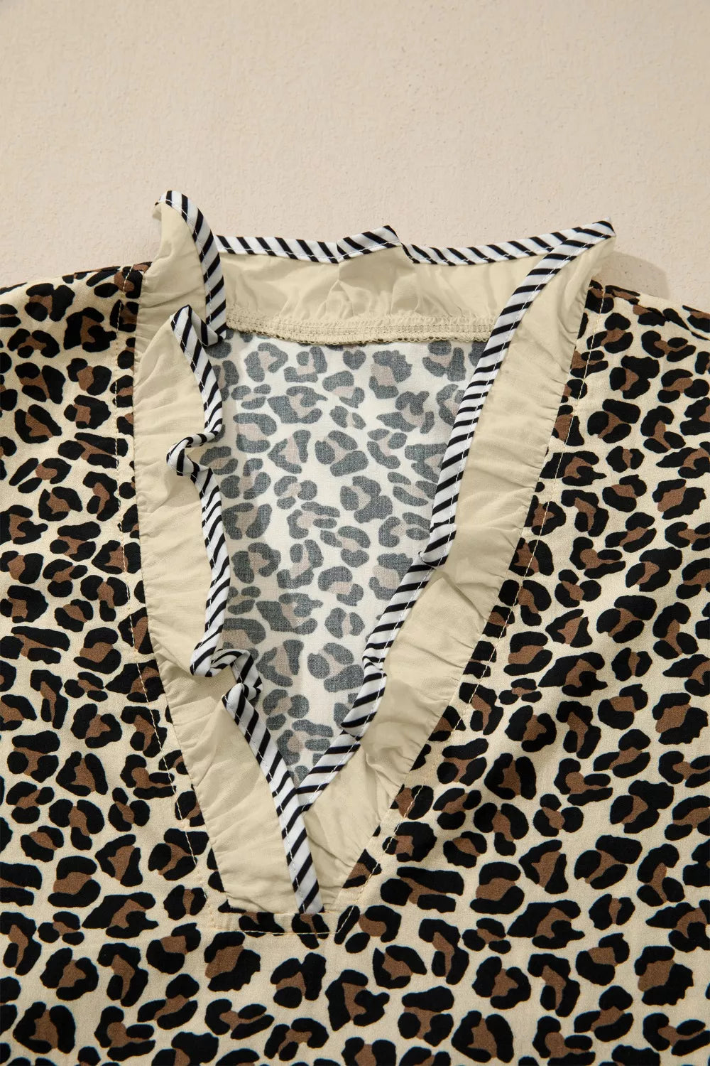 Leopard print mini dress with ruffle trim and striped neckline detail.