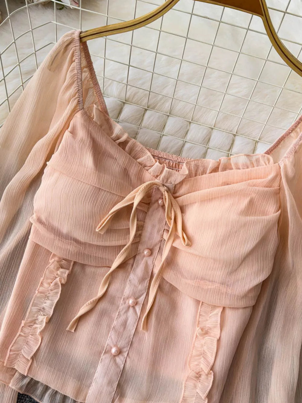 Romantic ruffled sleeve blouse in watermelon pink with a bow and pearl buttons.