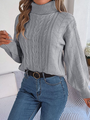 Light gray cable knit turtleneck sweater with drop shoulder and textured sleeves.