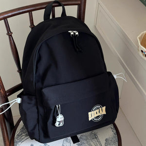 Black minimalist nylon backpack with front pocket, panda charm, and side drawstrings.