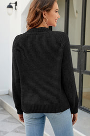 Black waffle knit raglan sleeve pullover sweater with mock neck and ribbed cuffs and hem.