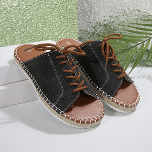 Black lace-up open-toe flats with espadrille sole and brown laces.