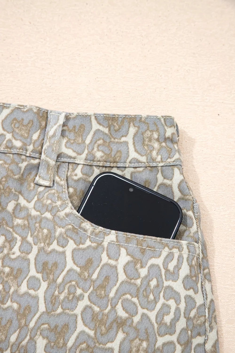 Denim shorts with leopard print and a phone in the pocket.