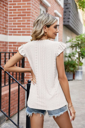 White eyelet blouse with lace trim and flutter sleeves, casual styling with denim shorts.
