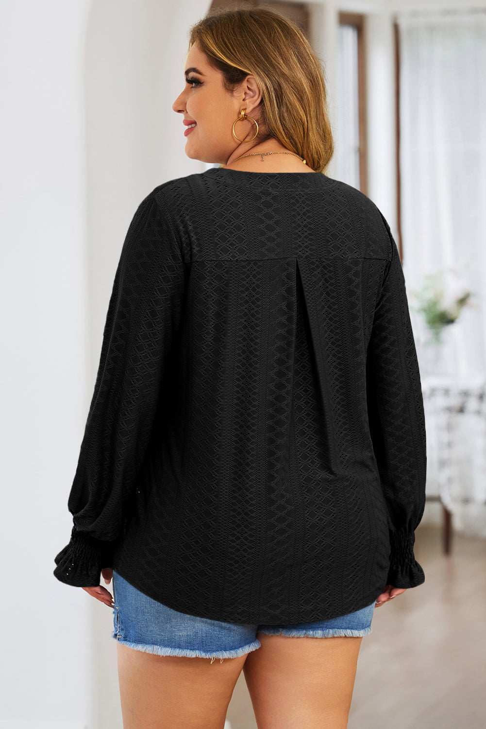 Black textured slit-neck blouse with shirred cuffs and a back pleat detail.