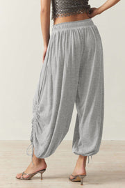Gathered ankle-tie balloon trousers in gray with cinched drawstring detail.