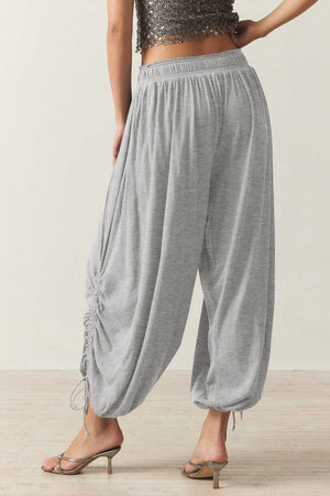 Gathered ankle-tie balloon trousers in gray with cinched drawstring detail.