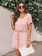 Blush pink off-shoulder romper with ruffle hem and drawstring waist.
