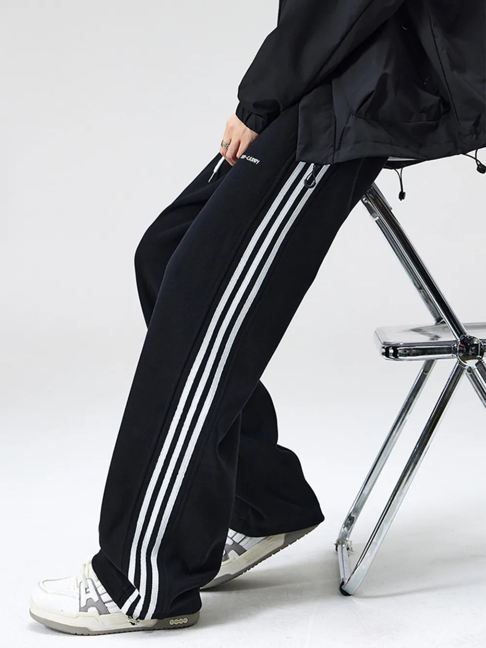 Black cotton sweatpants with white side stripes and drawstring waist.