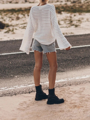 White open-knit sweater with bell sleeves and a relaxed fit, paired with denim shorts.