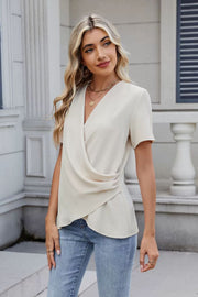 Cream draped front short sleeve blouse with a V-neckline and ruched side detail.
