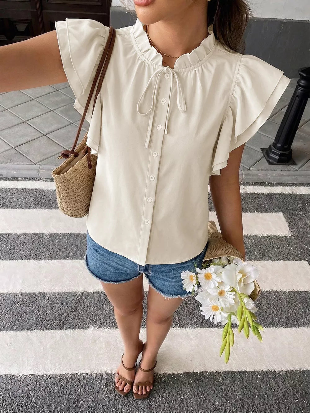Beige button-down shirt with ruffle sleeves and tie-neck detail.