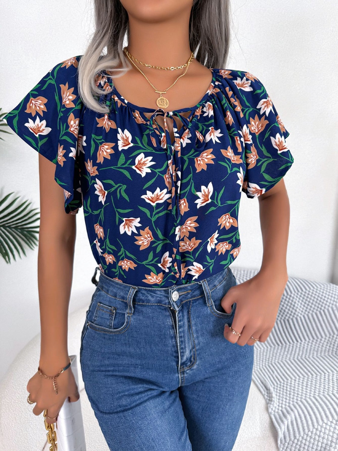 Dark blue floral ruffle sleeve tie-neck blouse with white and orange flowers