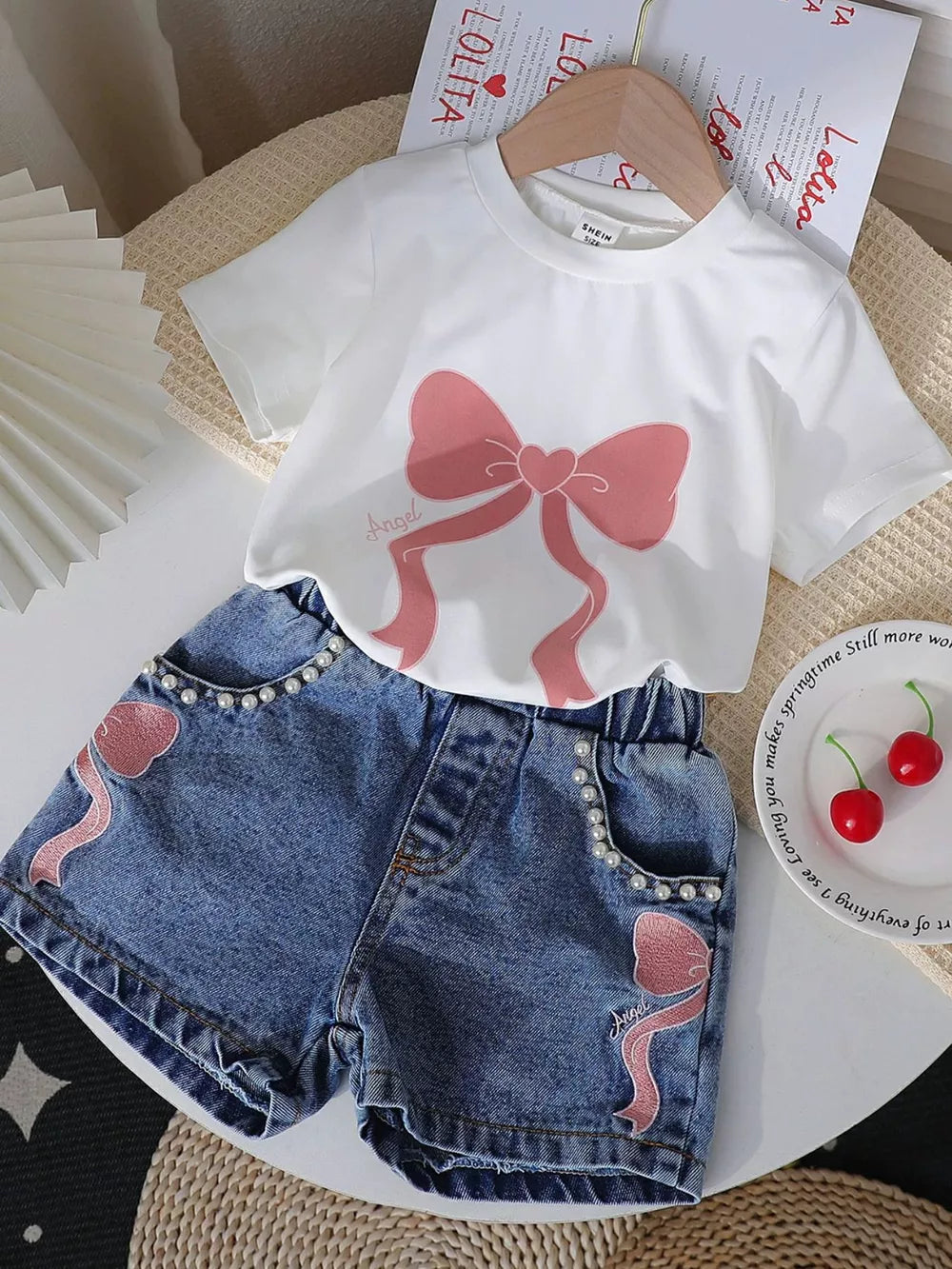 White tee with pink bow print and denim shorts with pearl trim and bow embroidery.