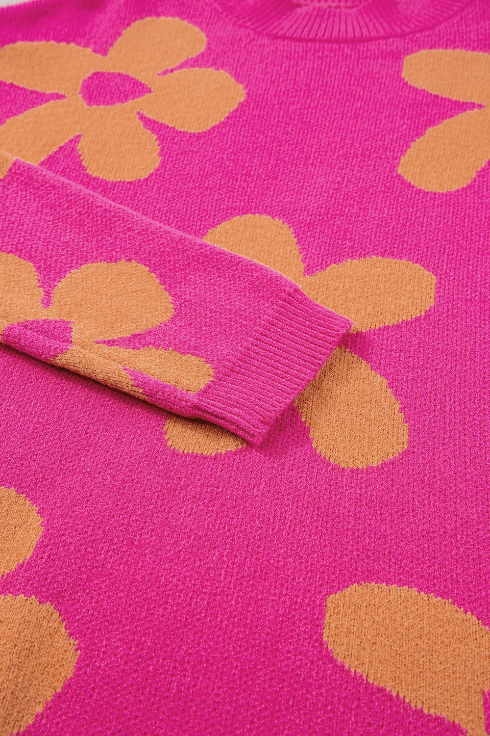 Cerise knit sweater with oversized retro floral pattern and ribbed cuffs.