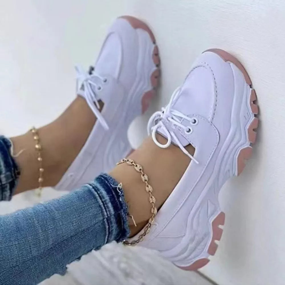 White lace-up sneakers with pink sole details and a chunky sole.